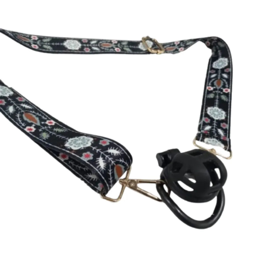Floral-patterned belt with a black plastic chastity cage on a white background