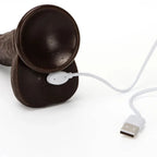 Black dildo with a white USB cable and connector on a white background