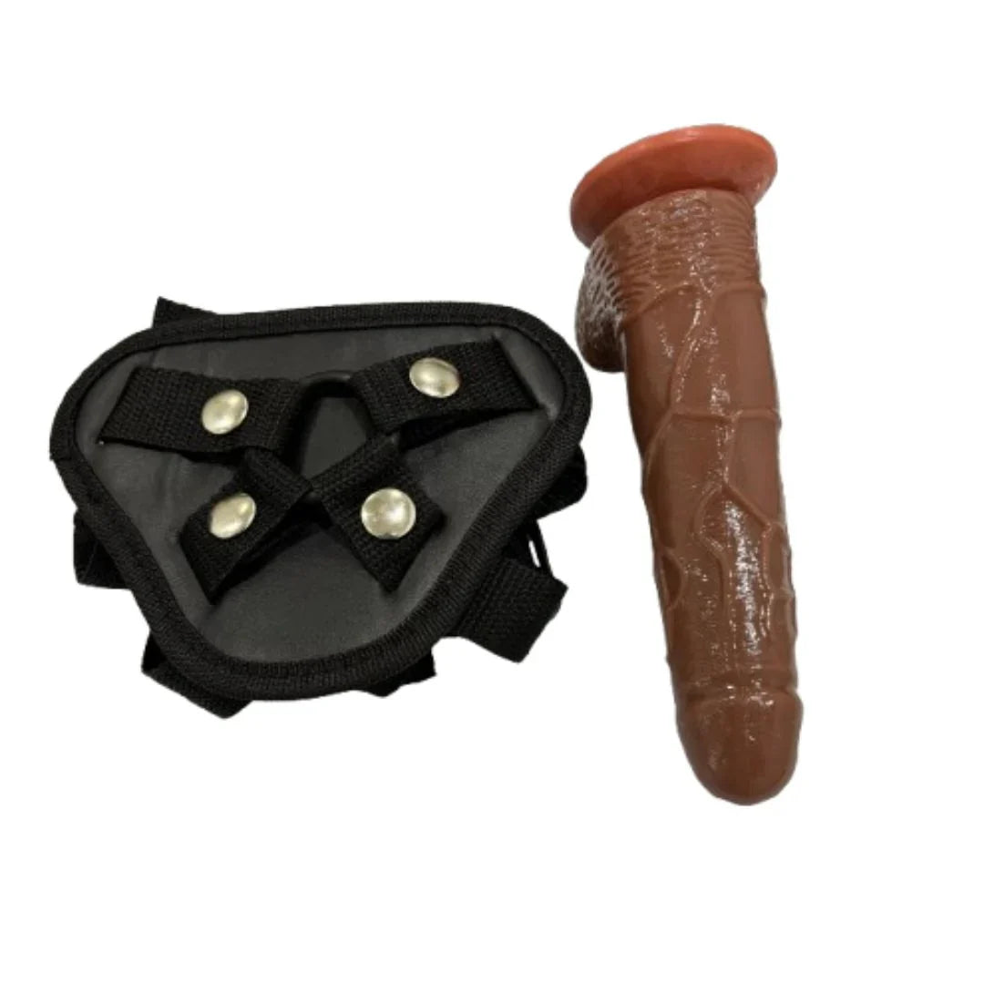 Black leather belt with metallic buttons next to a brown dildo on a white background