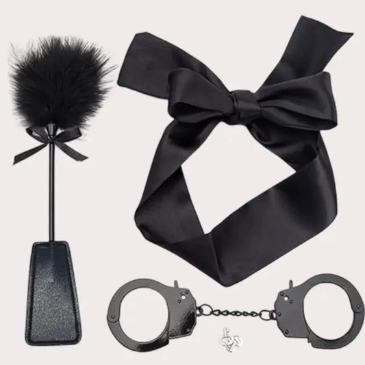 Black satin bow, black feather duster, and black handcuffs on a white background