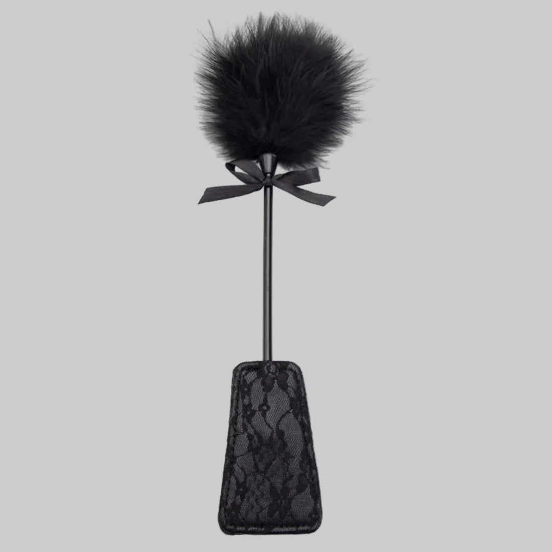 Black feathered paddle with lace design on a gray background